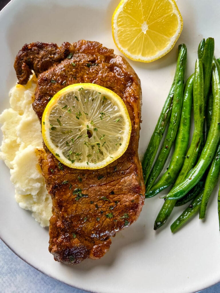 lemon pepper steak with lemon, mashed potatoes, and green beans