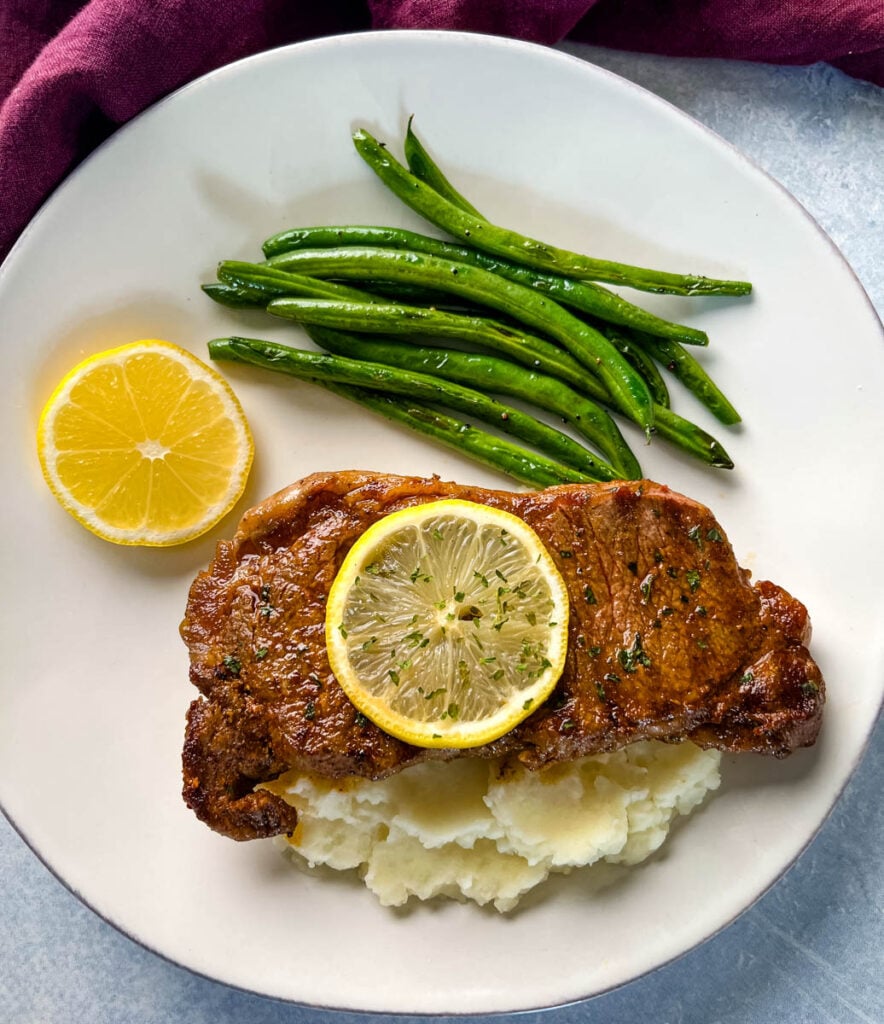 lemon pepper steak with lemon, mashed potatoes, and green beans