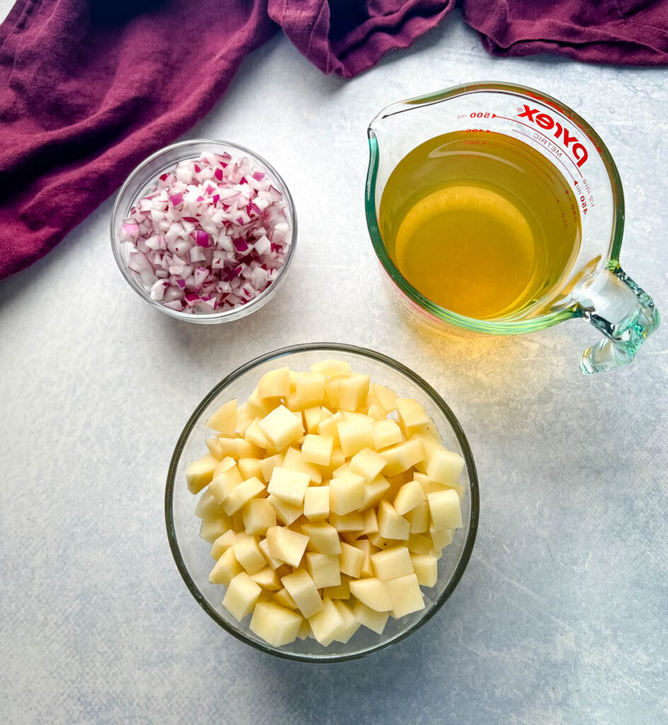 chopped onions, broth, and diced potatoes in a glass bowl