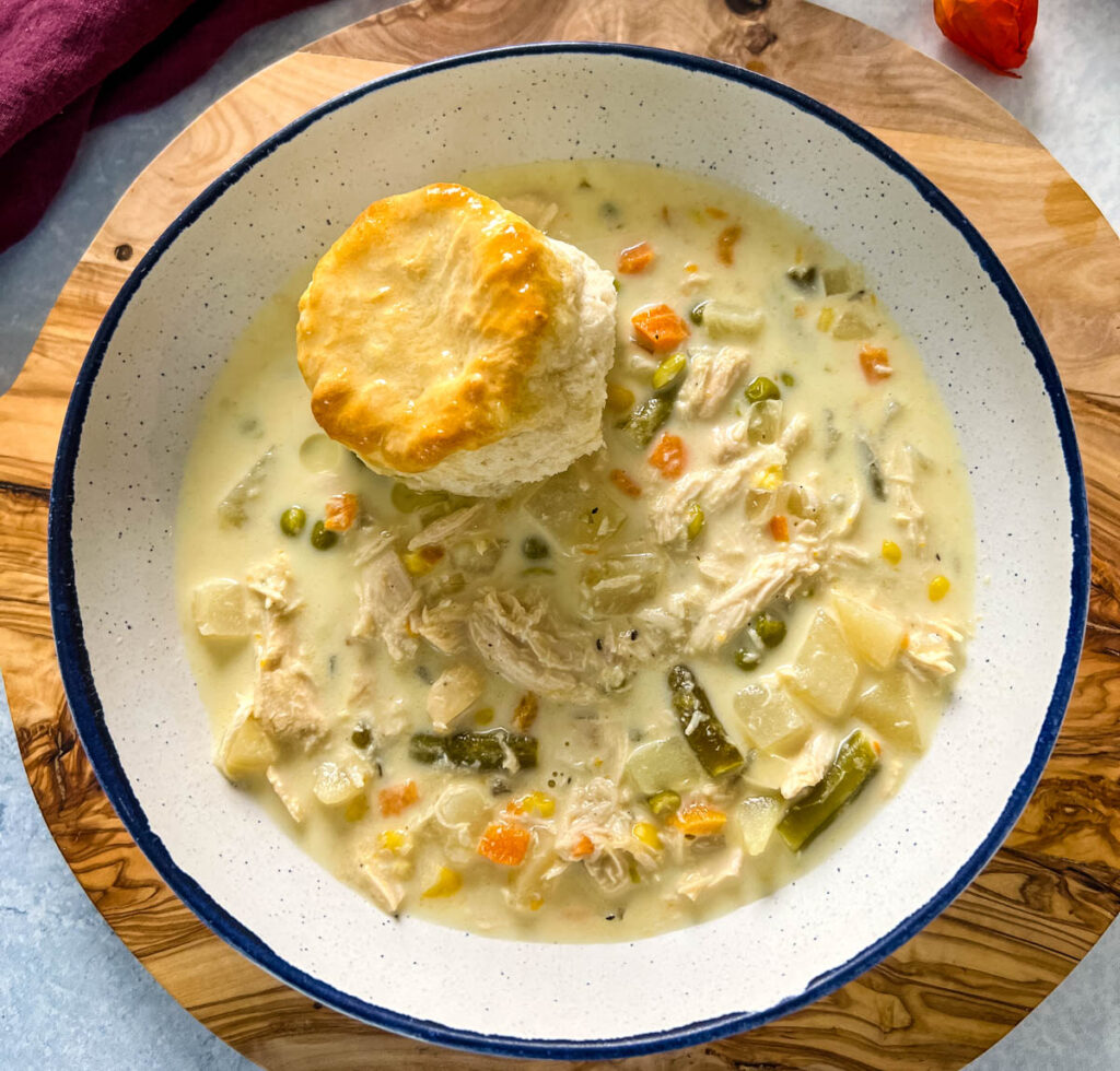 slow cooker crockpot chicken pot pie in a bowl with a biscuit