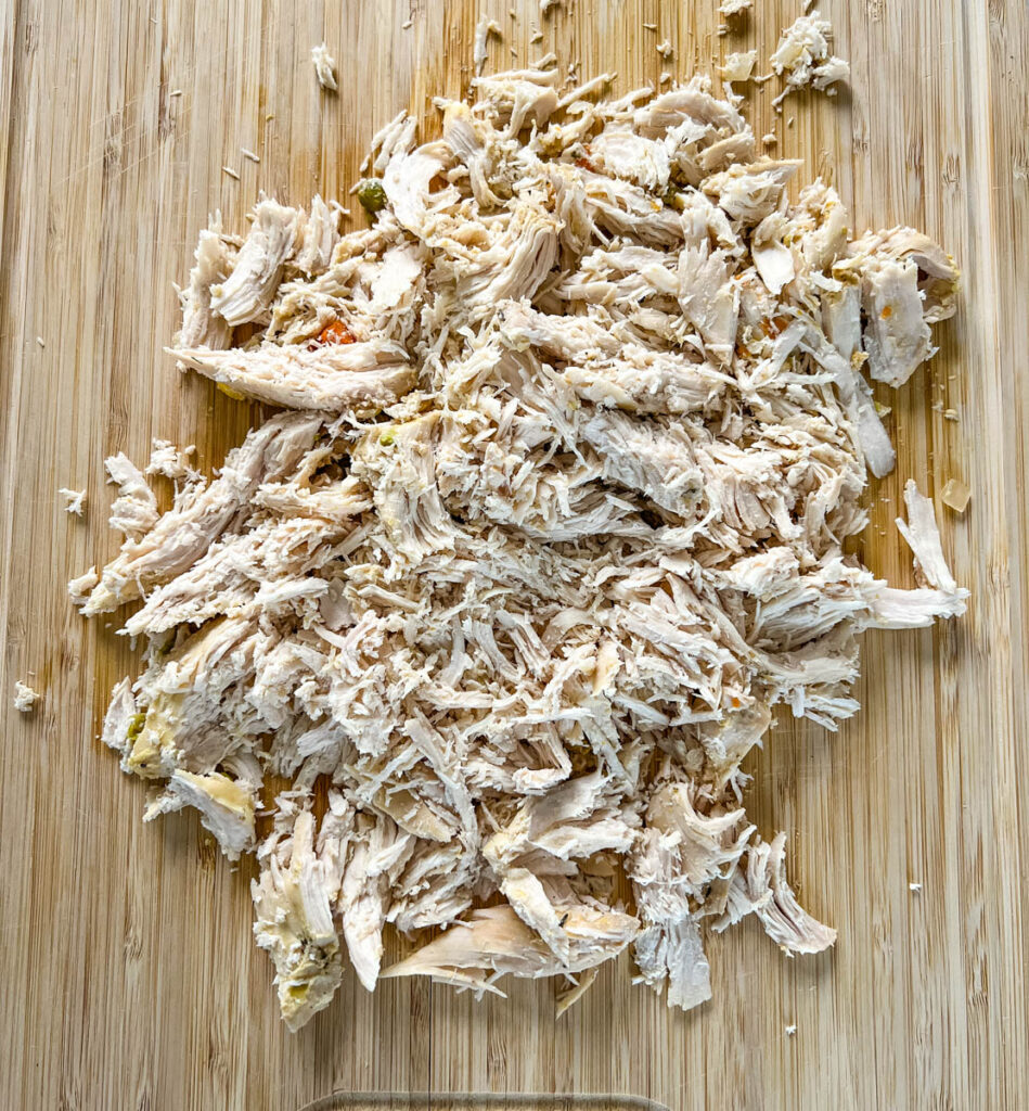 shredded chicken on a bamboo cutting board