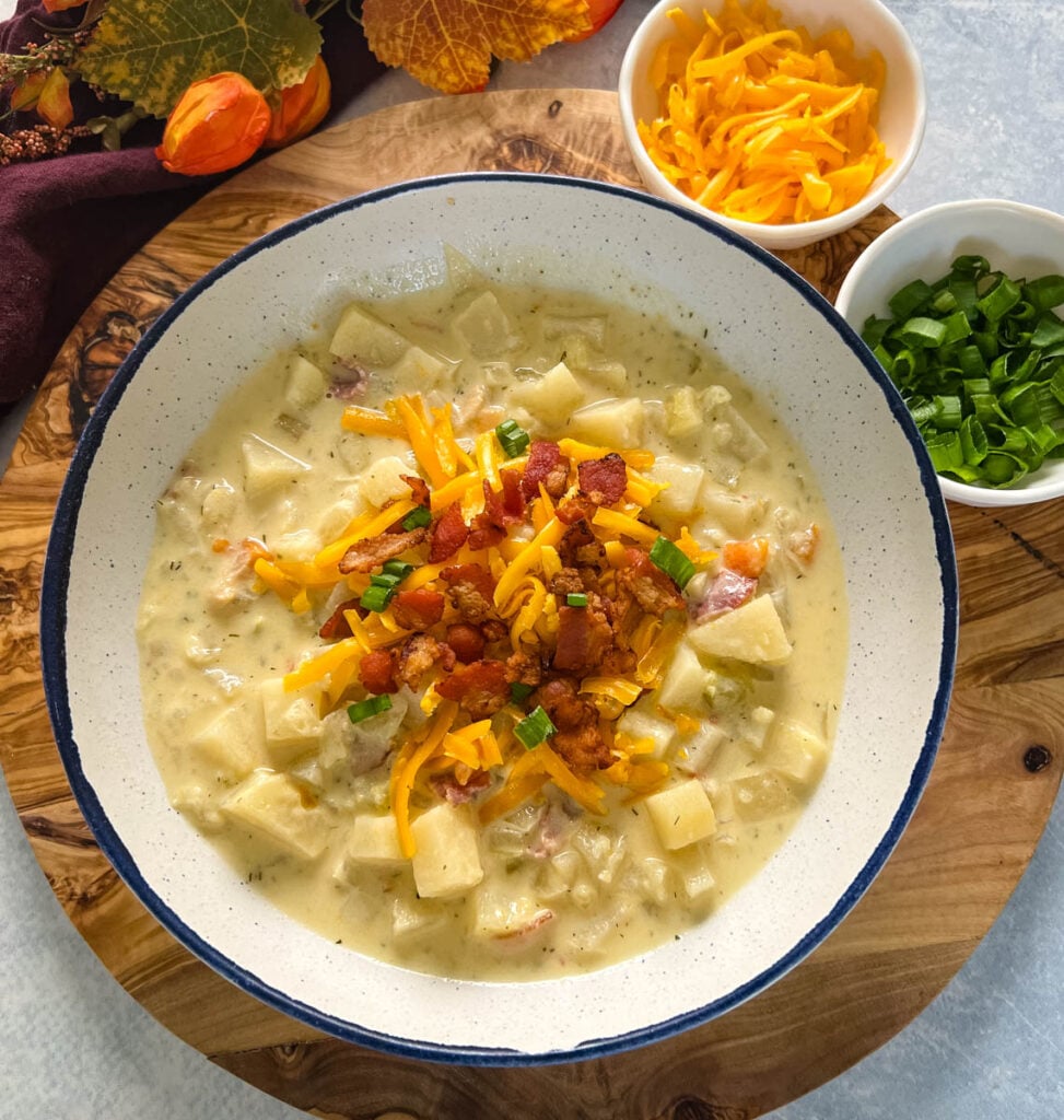 slow cooker loaded potato soup in a white bowl with bacon and cheese