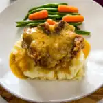 slow cooker crockpot oxtails with mashed potatoes, gravy, green beans, and carrots on a plate