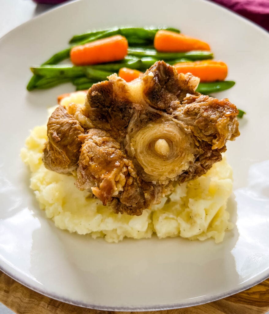 slow cooker crockpot oxtails with mashed potatoes, green beans, and carrots on a plate