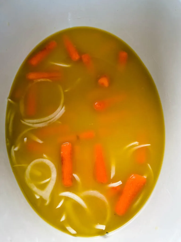 broth, carrots, and onions in a Crockpot slow cooker