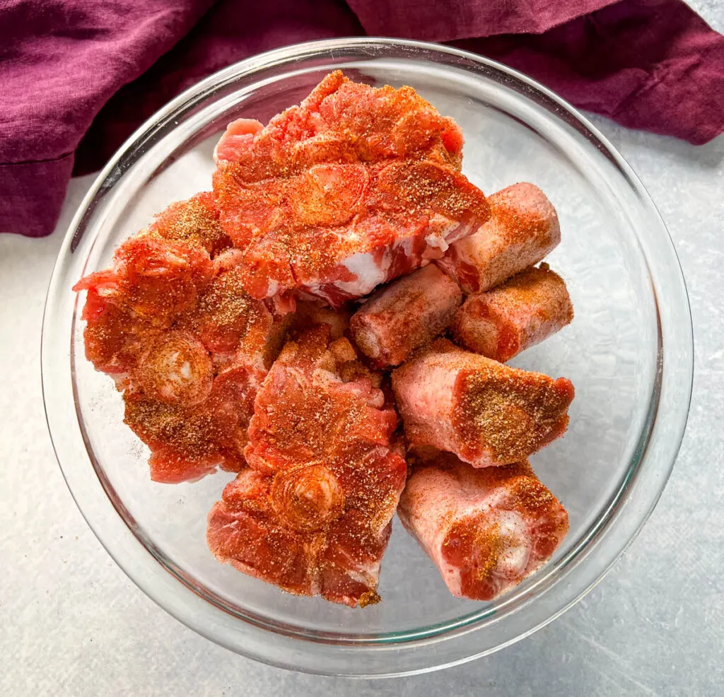 raw seasoned oxtails in a glass bowl