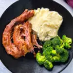 smoked turkey necks, mashed potatoes, and broccoli in a black plate