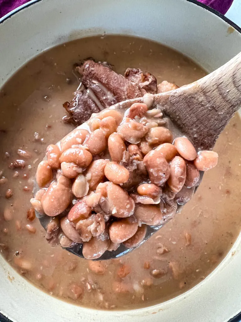 a wooden spoon of pinto beans and ham hocks