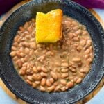 pinto beans, ham hocks, and cornbread in a black bowl