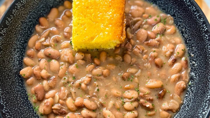 pinto beans, ham hocks, and cornbread in a black bowl