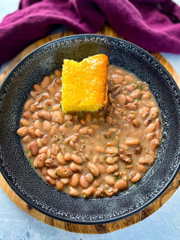 pinto beans, ham hocks, and cornbread in a black bowl