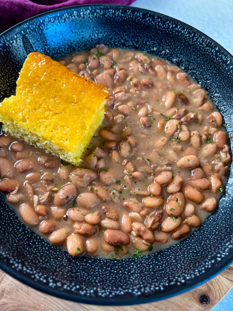 pinto beans, ham hocks, and cornbread in a black bowl