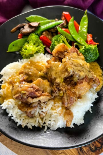 oxtail on a plate with white rice, gravy, and vegetables