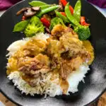 oxtail on a plate with white rice, gravy, and vegetables