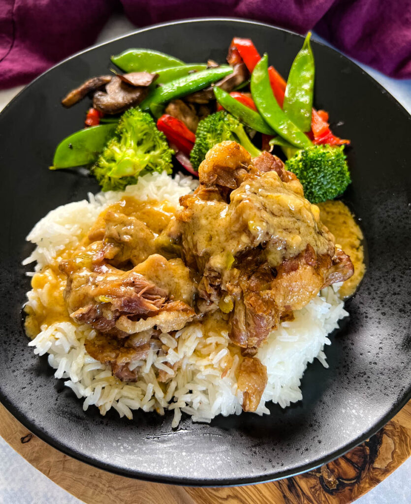 oxtail on a plate with white rice, gravy, and vegetables