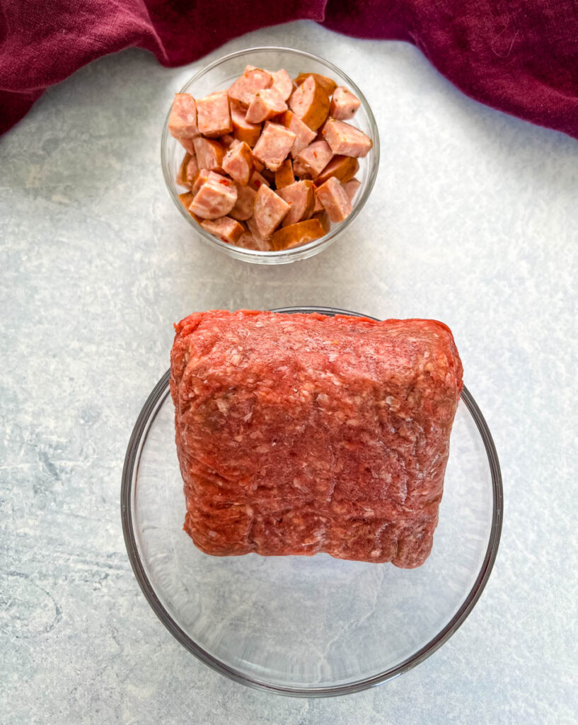 raw ground beef and andouille sausage in glass bowls