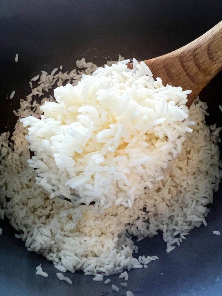 cooked white rice in a wooden spoon