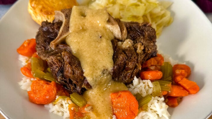 beef neck bones with gravy, cabbage, rice, and carrots on a plate