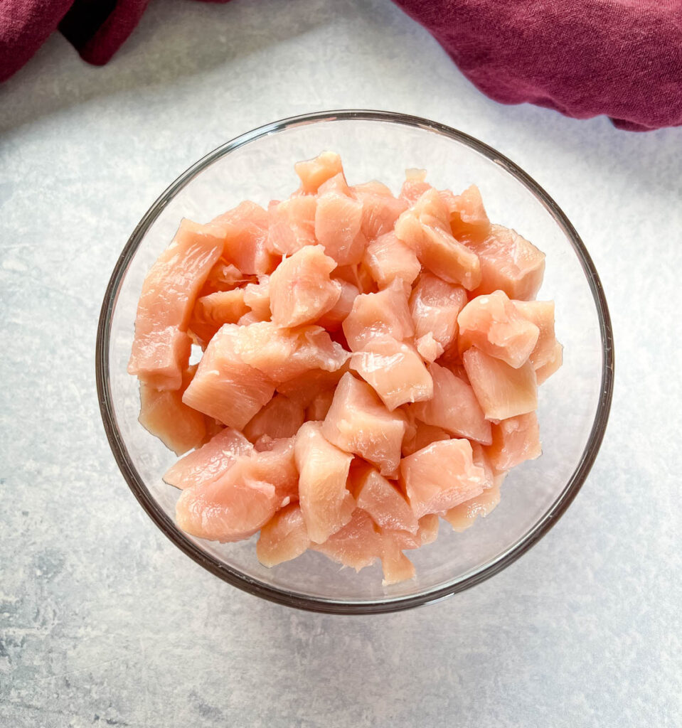 raw chicken breasts sliced into small pieces in a glass bowl