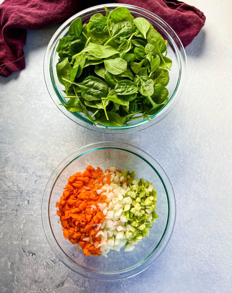 fresh spinach, carrots, celery, and onions in separate bowls