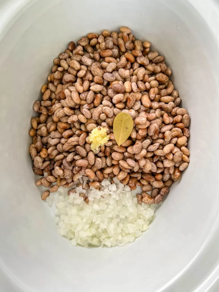 dry pinto beans, onions, bay leaves, and garlic in a slow cooker crockpot