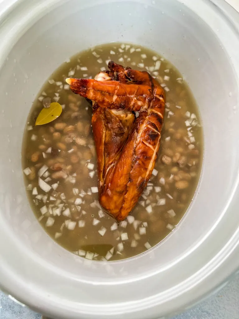 broth, smoked turkey, dry pinto beans, onions, bay leaves, and garlic in a slow cooker crockpot