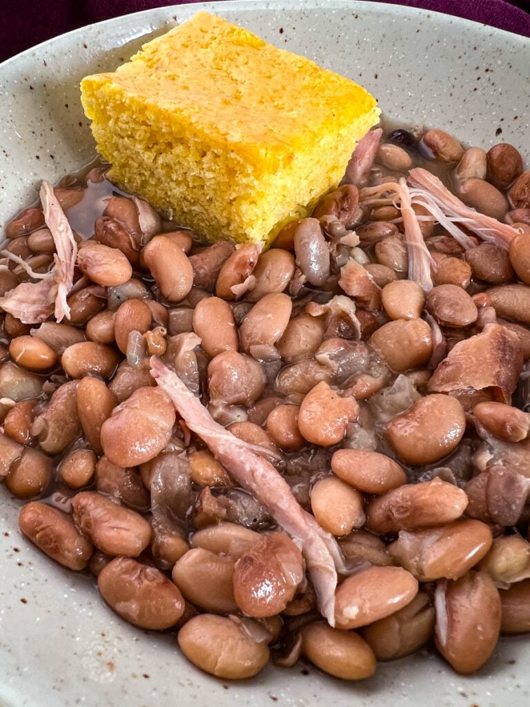slow cooker crockpot pinto beans in a bowl with cornbread