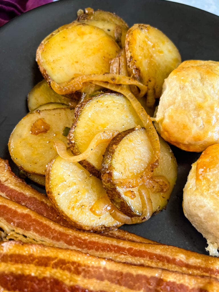 fried potatoes, bacon, and biscuits on a plate