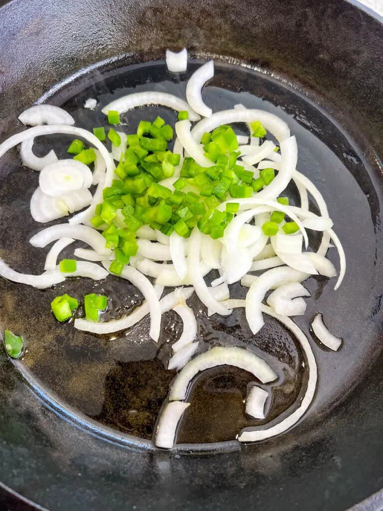 onions and green peppers in a cast iron skillet