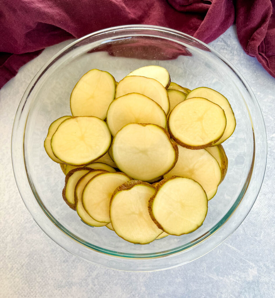 russet potatoes sliced into rounds in a glass bowl