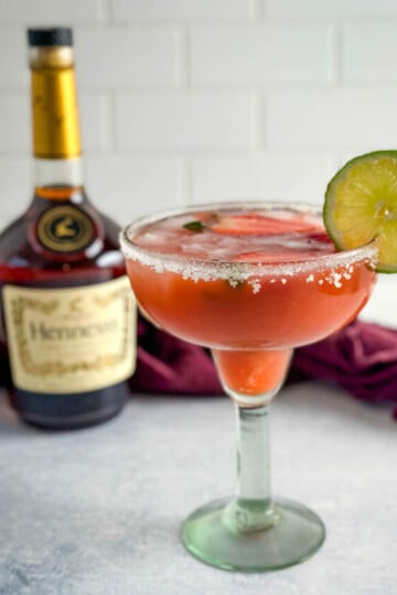Hennessy margarita in a glass with strawberries and lime