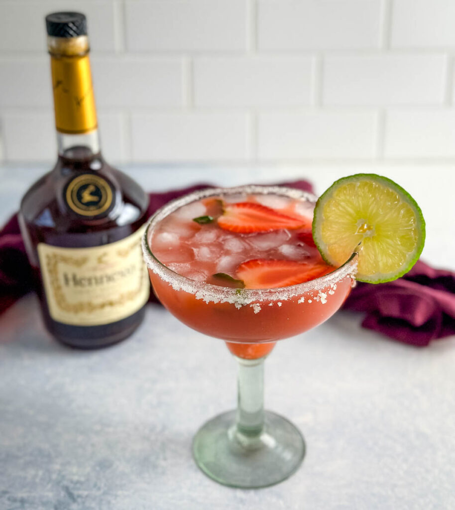 Hennessy margarita in a glass with strawberries and lime