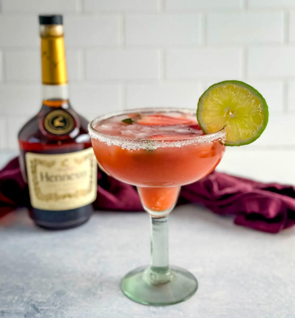 Hennessy margarita in a glass with strawberries and lime