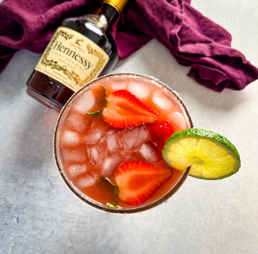 Hennessy margarita in a glass with strawberries and lime