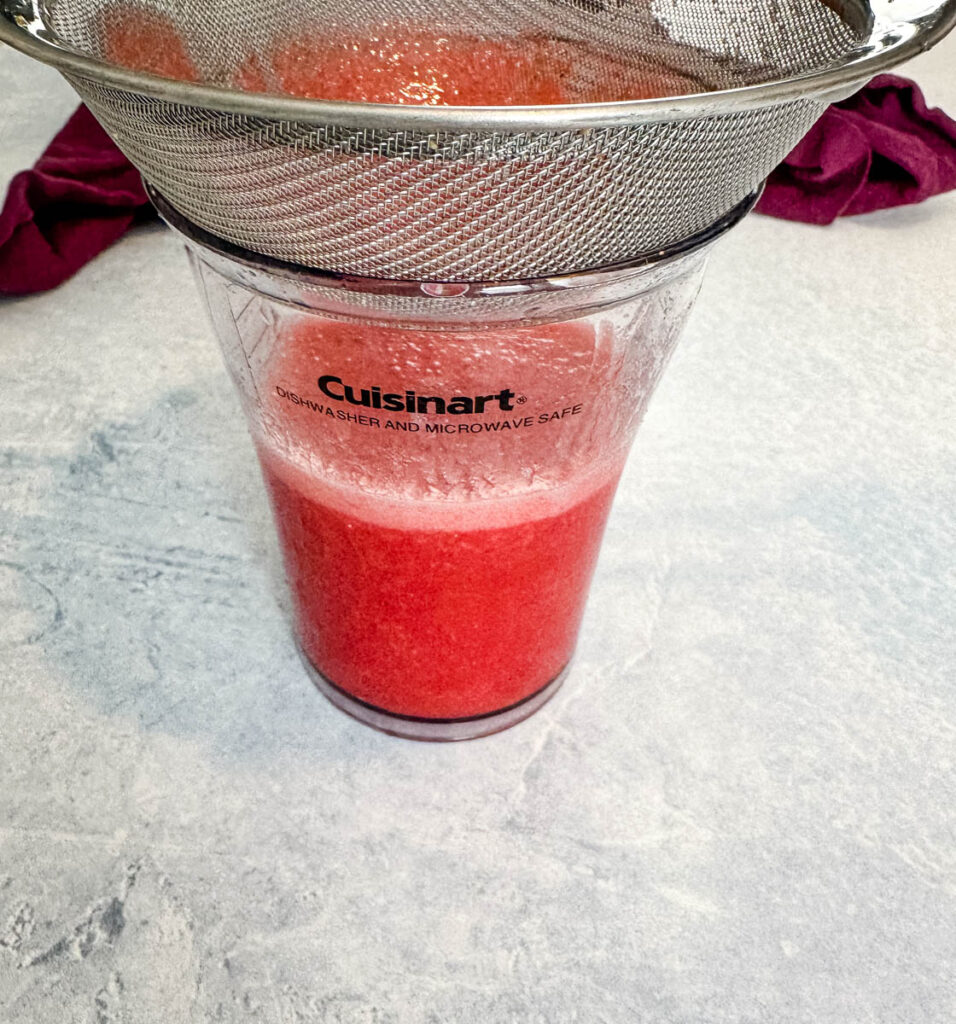 pureed strawberries in a strainer and cup