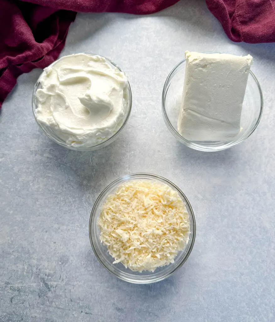 Greek yogurt, cream cheese, and Parmesan cheese in separate glass bowls