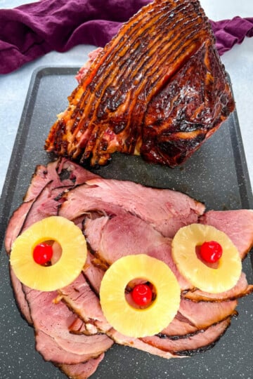 Traeger smoked ham sliced on a plate with pineapples and cherries