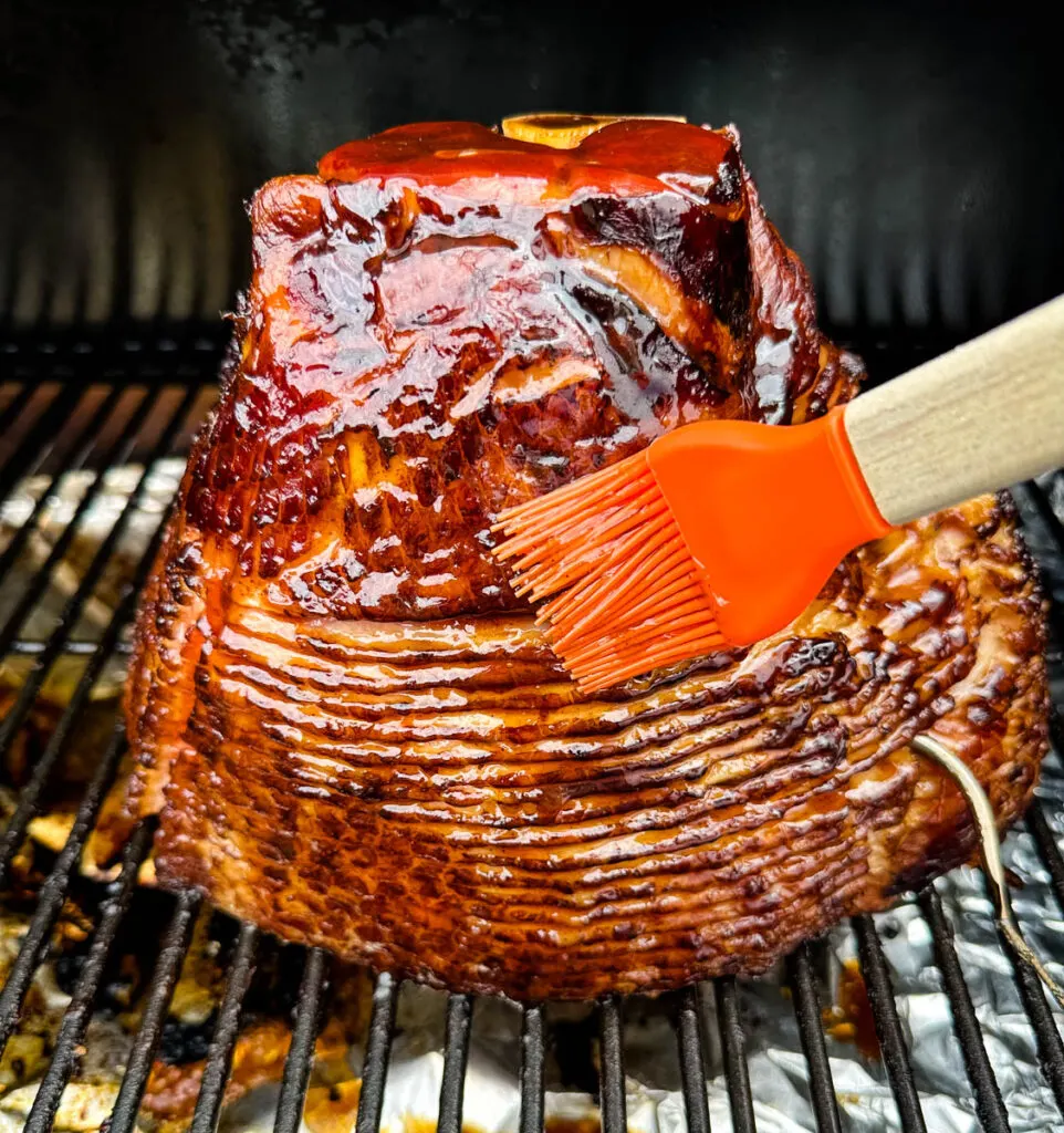 ham on a Traeger pellet grill brushed with honey brown sugar glaze