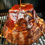 ham on a Traeger pellet grill brushed with honey brown sugar glaze