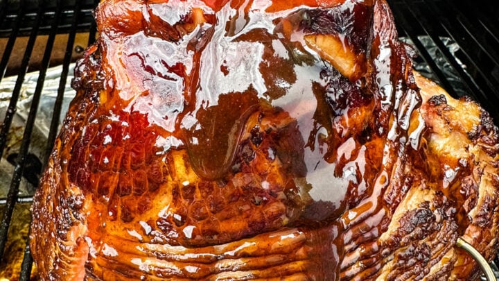 ham on a Traeger pellet grill brushed with honey brown sugar glaze
