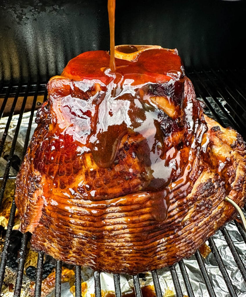 ham on a Traeger pellet grill brushed with honey brown sugar glaze