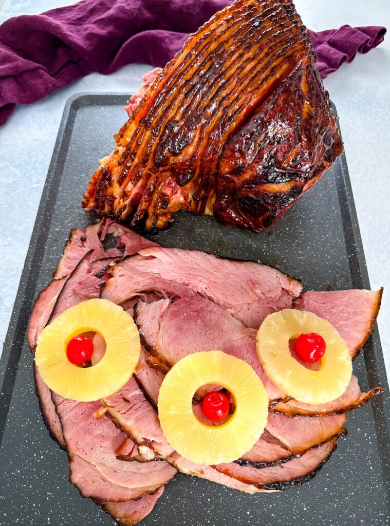 Traeger smoked ham sliced on a plate with pineapples and cherries