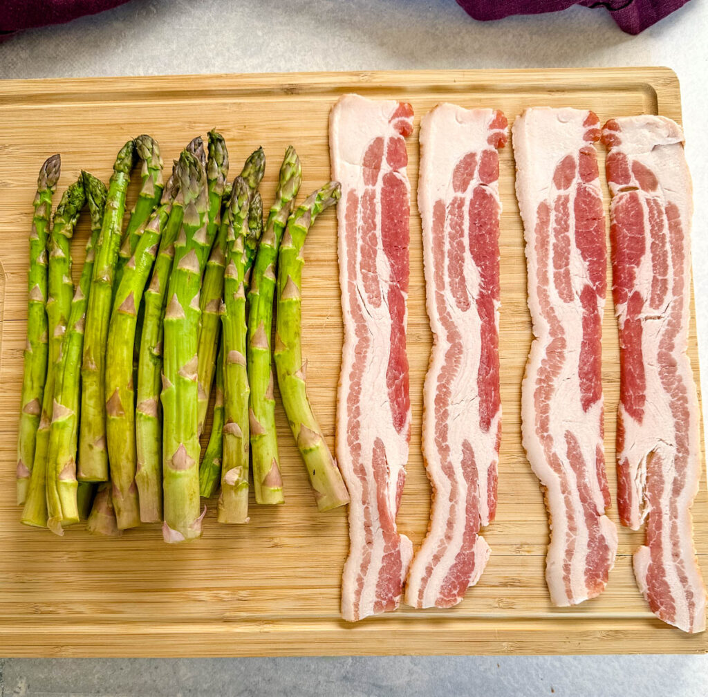 fresh asparagus and bacon on a wooden cutting board