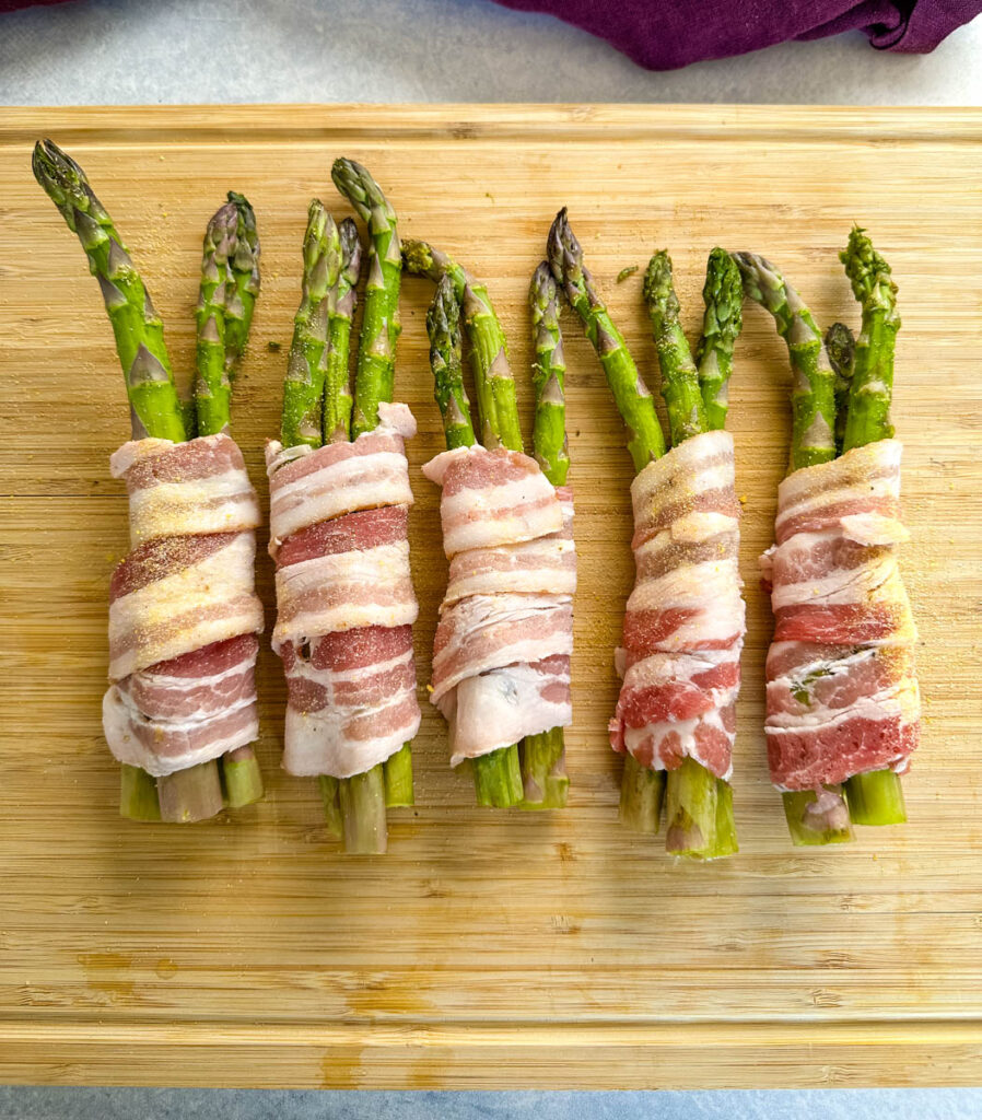 bacon wrapped asparagus on a wooden cutting board