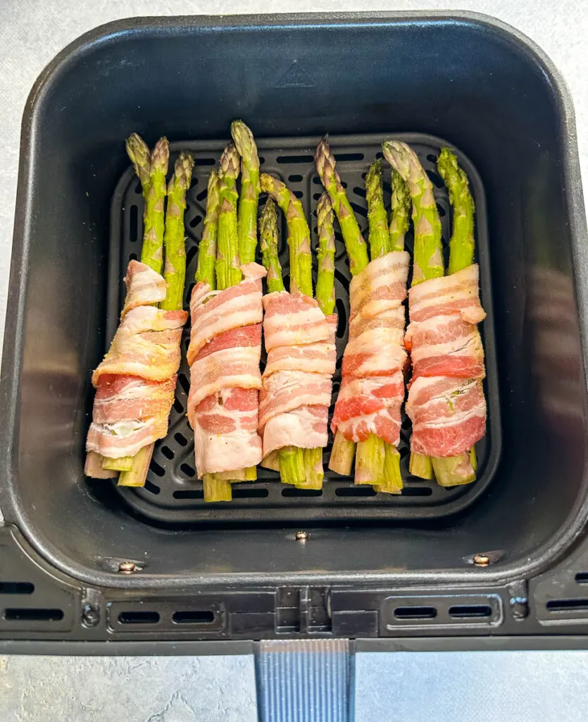 uncooked bacon wrapped asparagus in an air fryer
