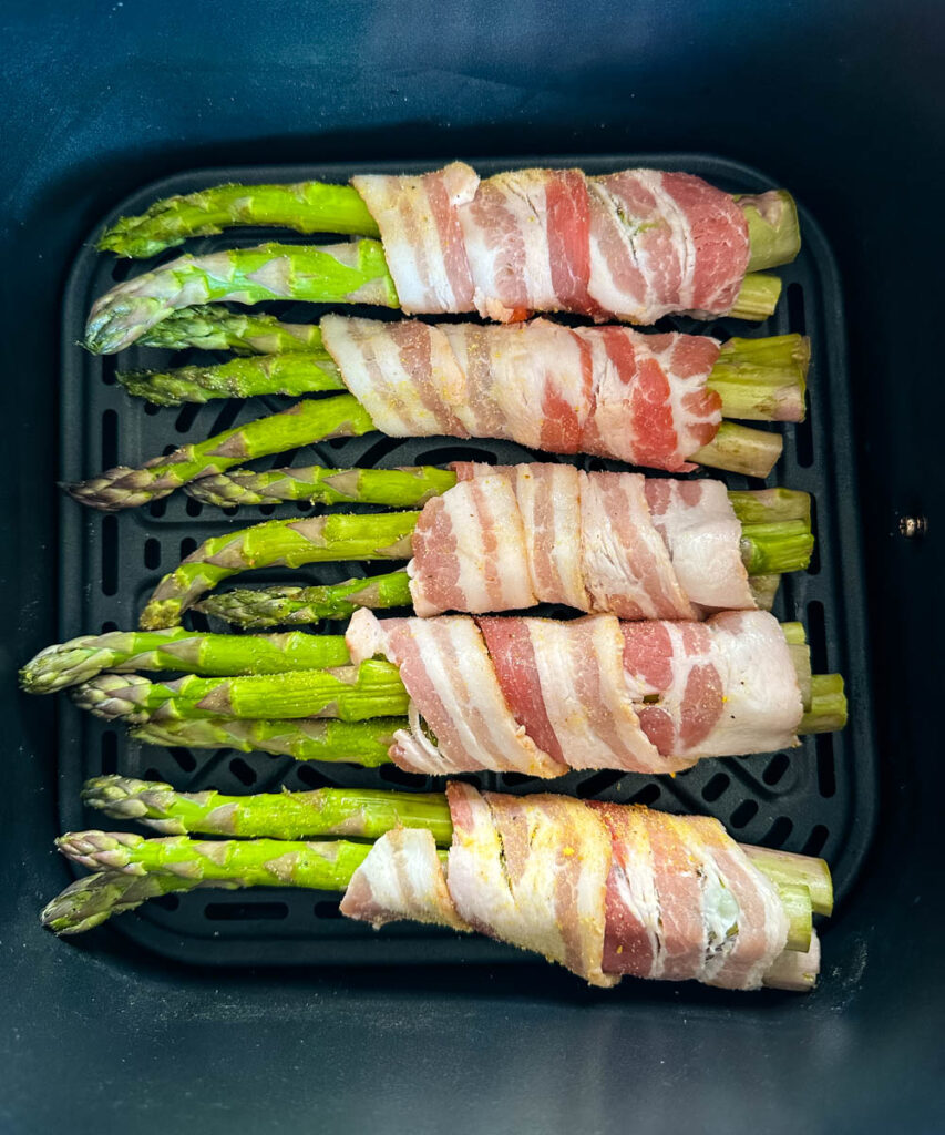 uncooked bacon wrapped asparagus in an air fryer