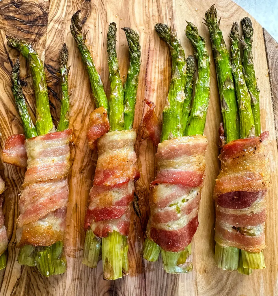 air fryer bacon wrapped asparagus on a wooden cutting board
