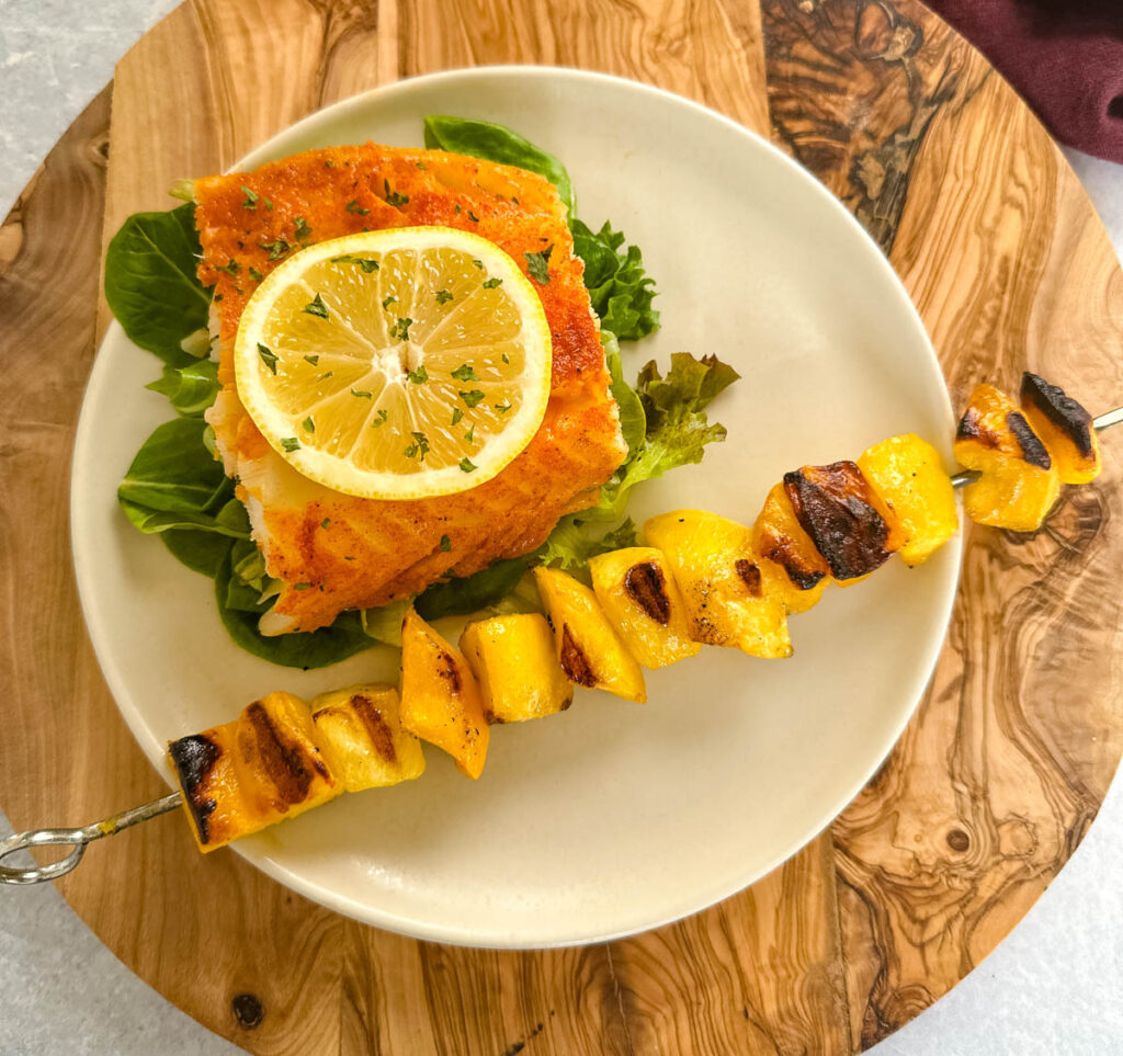 grilled cod with lemon and grilled mango on a plate