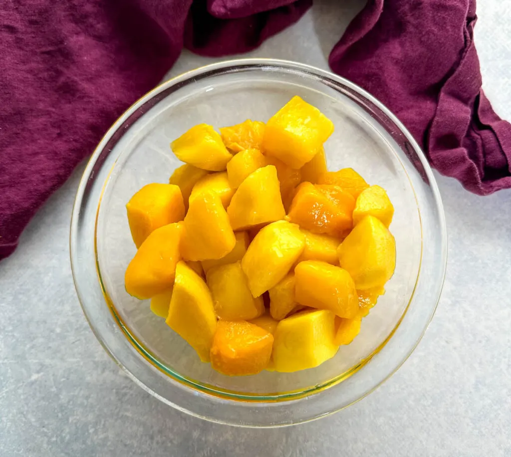 frozen thawed mango sliced into chunks in a glass bowl