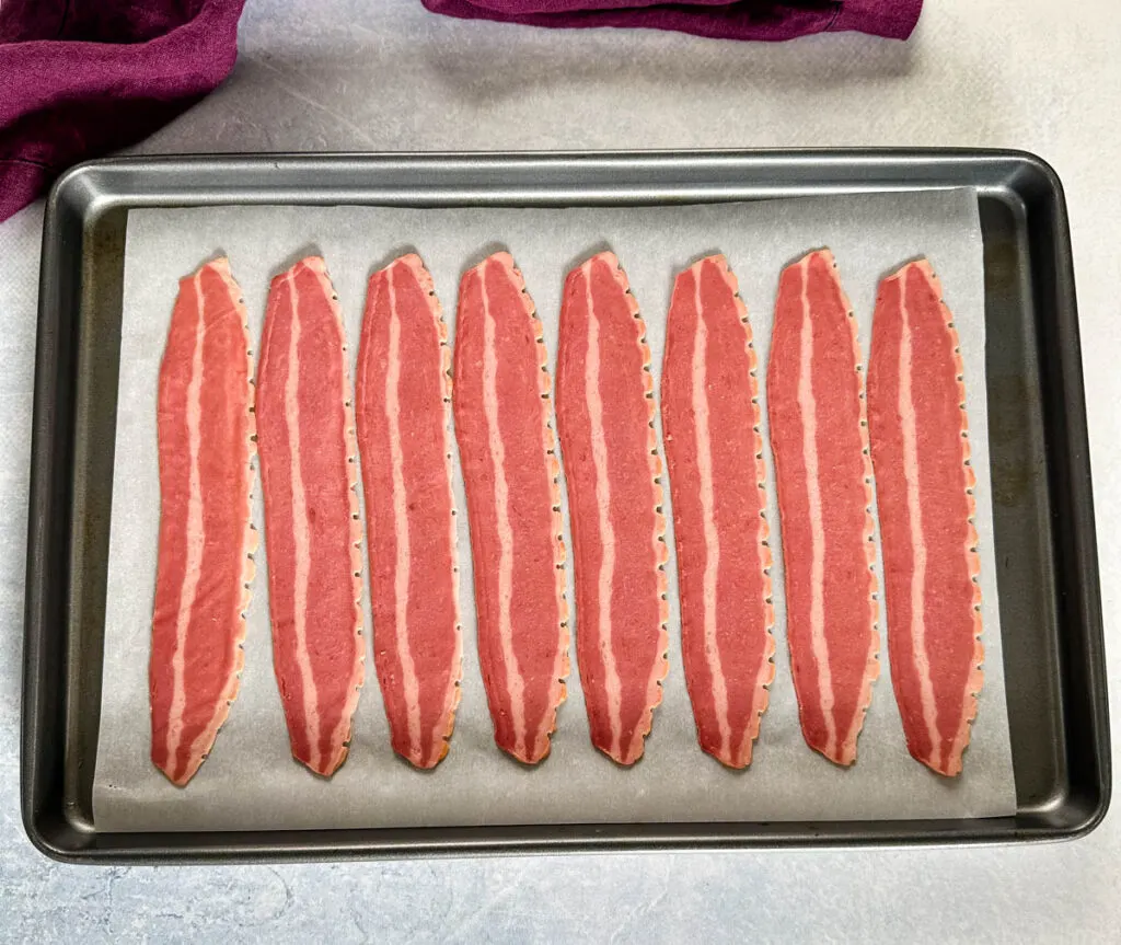 uncooked turkey bacon on a sheet pan with parchment paper